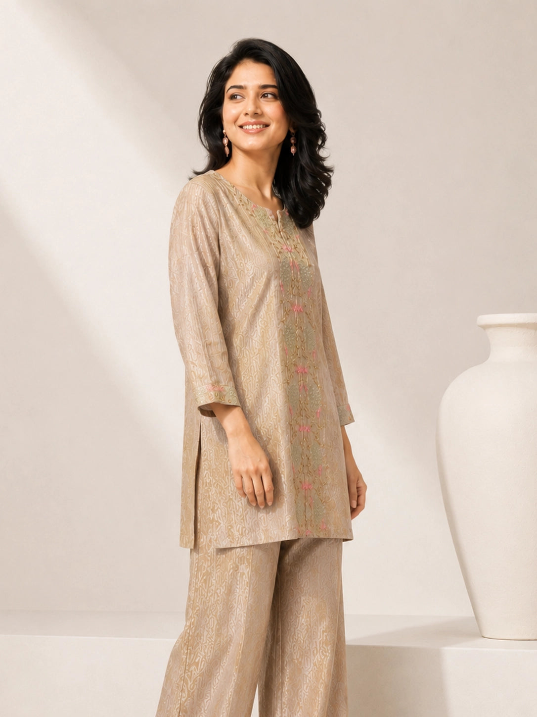 Woman wearing a shimmering grey embroidered kurta and matching pants, styled for a festive occasion.
