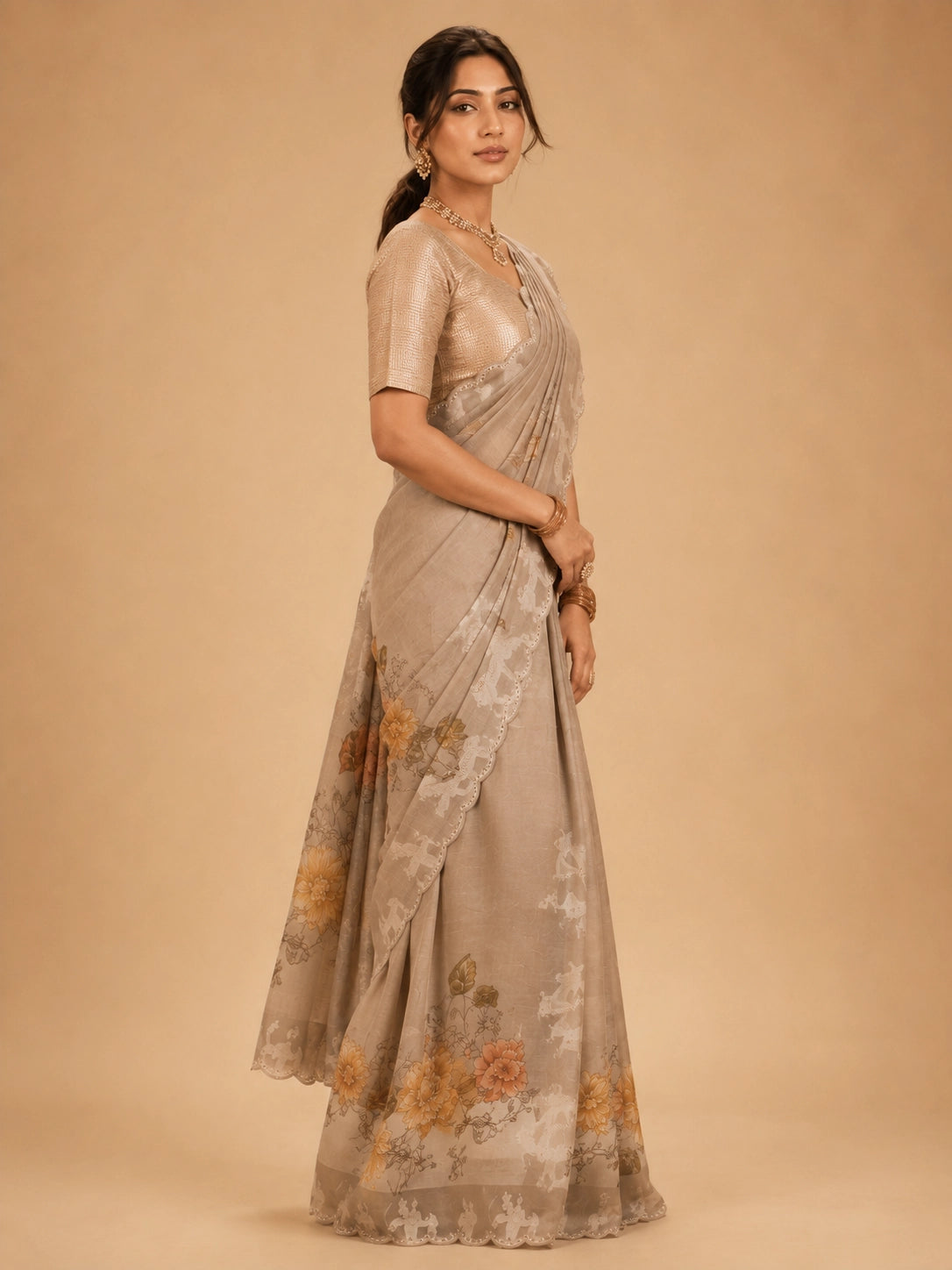 Woman wearing an elegant  peach floral saree with animal motifs and a golden blouse.