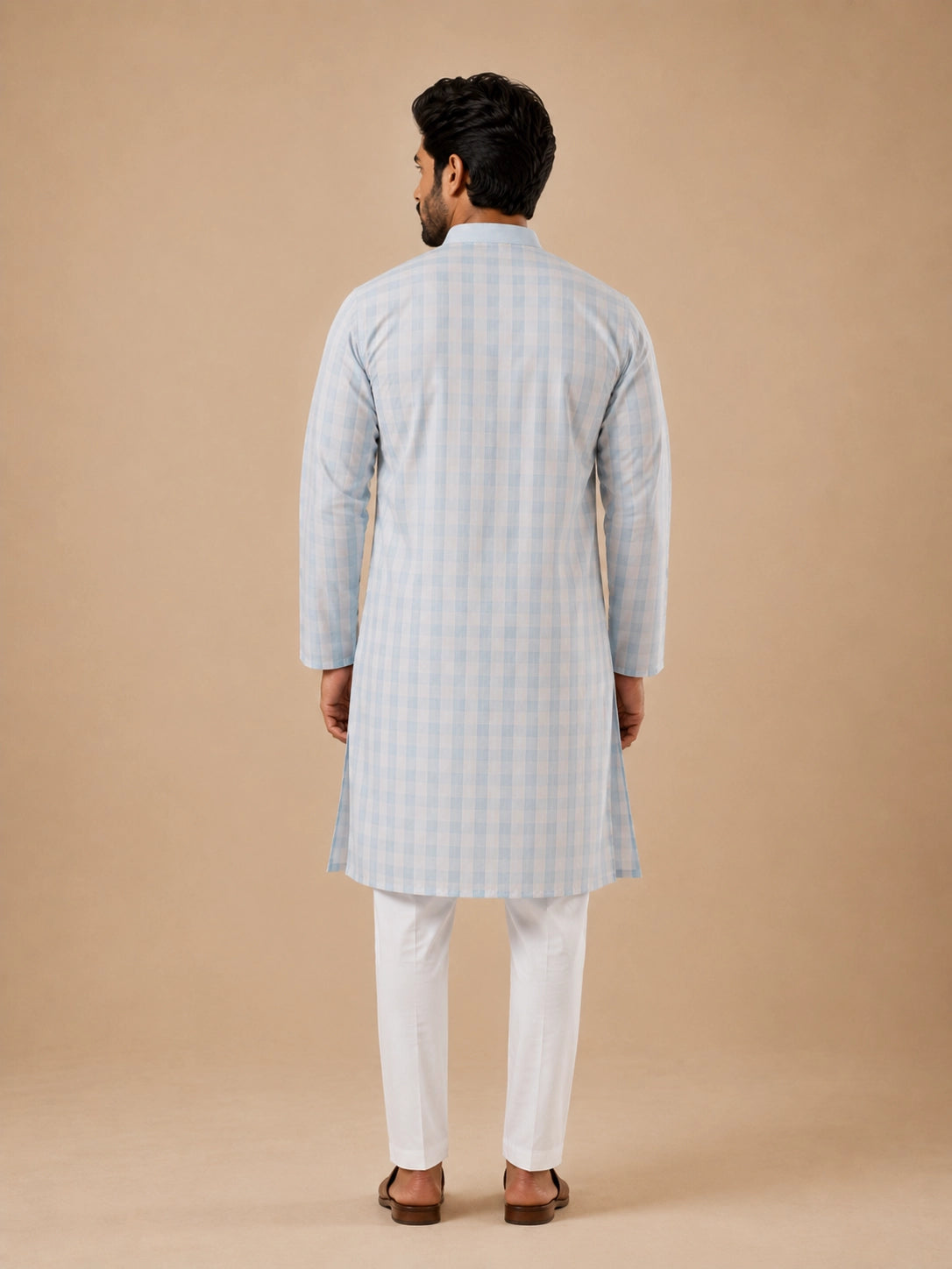 Man wearing a light sky blue and white checkered kurta with white pajamas.