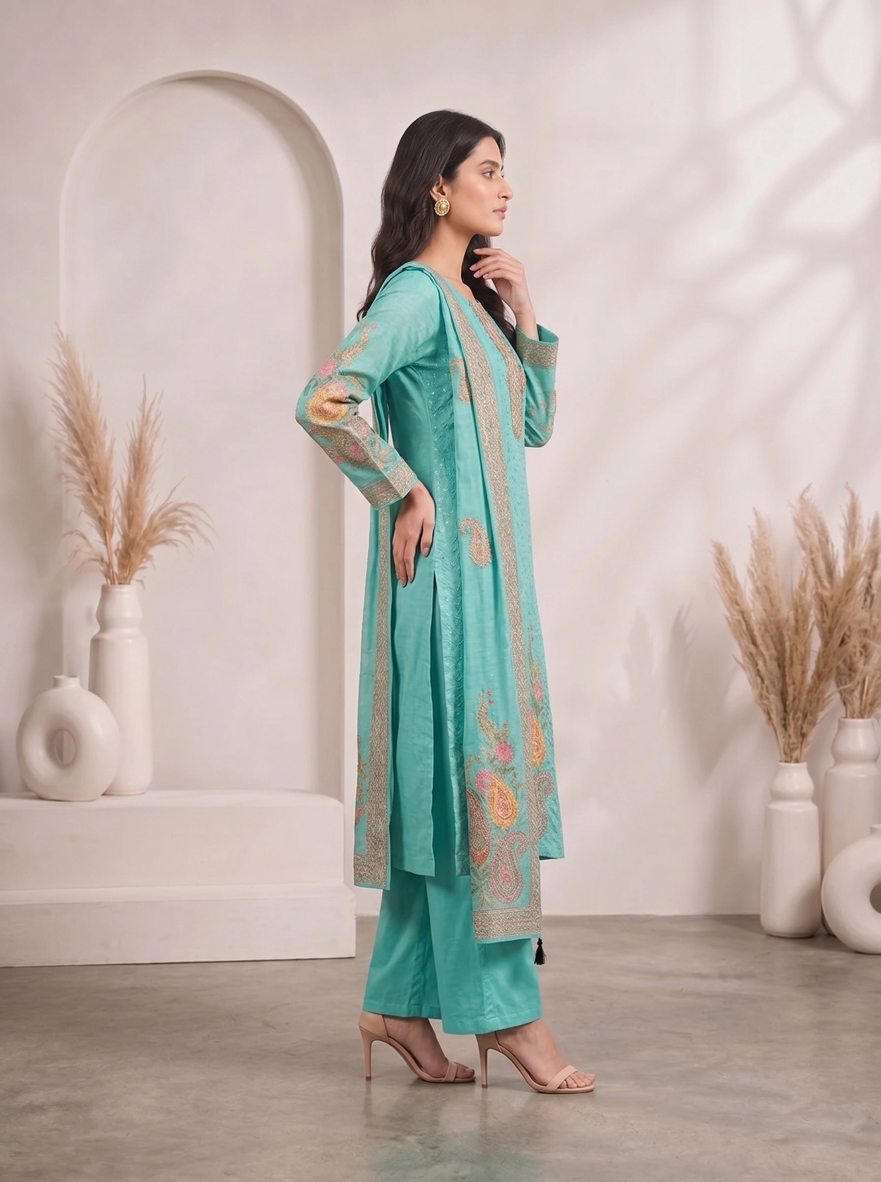 Woman wearing a teal kurti set with floral prints and matching palazzo pants, draped with a dupatta.