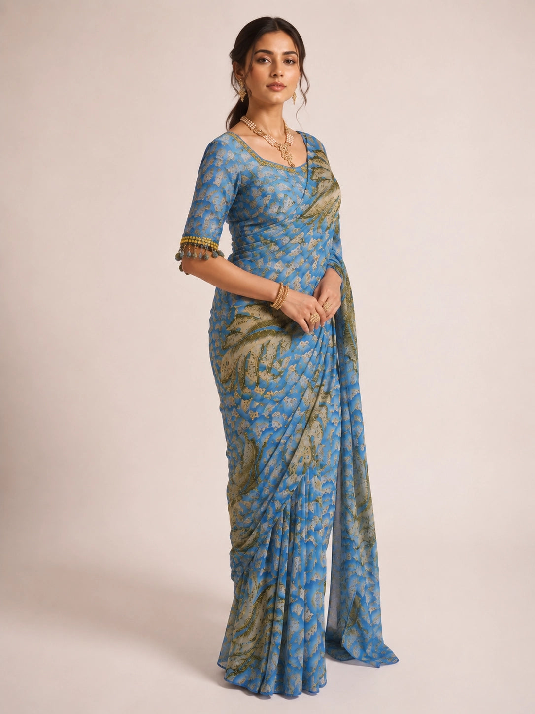 Woman wearing a sky blue  printed saree with olive feather patterns.