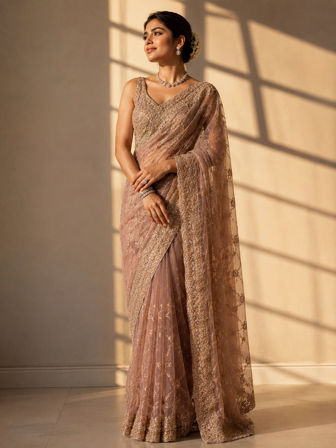 Woman in an elegant pink S3 embellished saree with intricate gold work and sleeveless blouse.