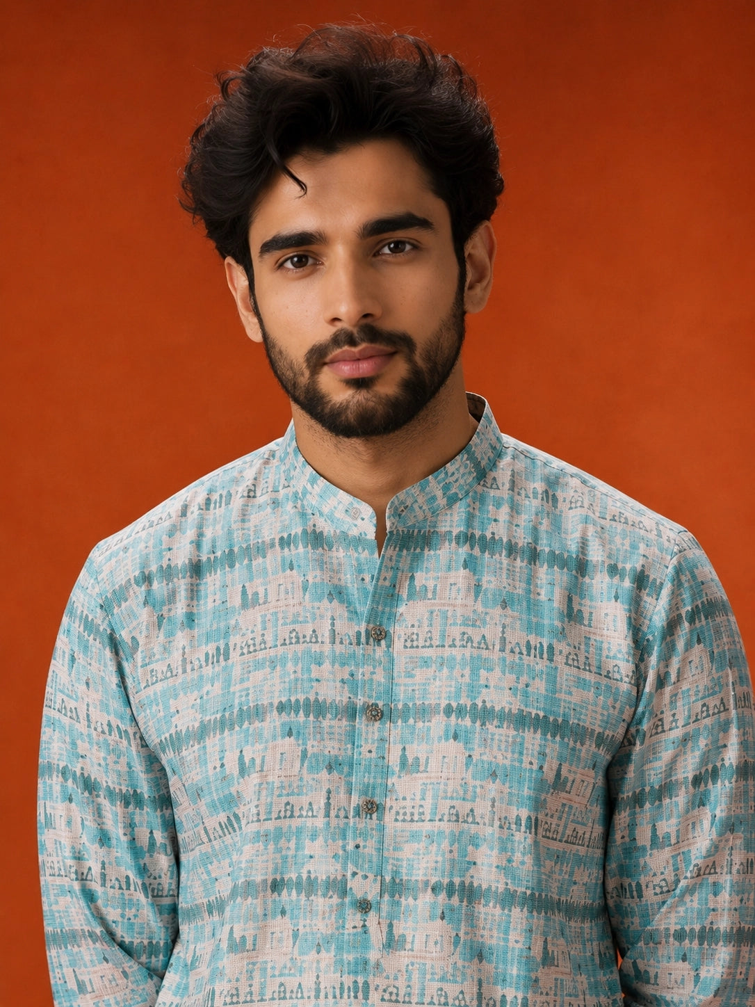 Man wearing an aqua and white printed kurta with white pajamas and brown loafers.
