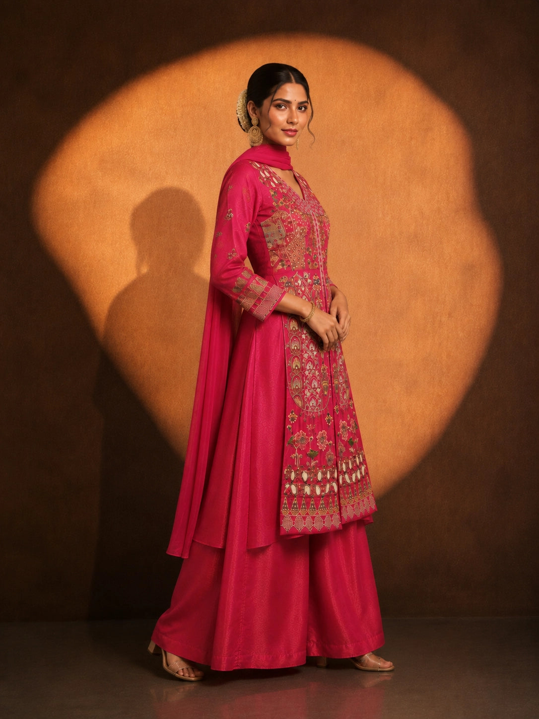 Woman in a vibrant rani pink embroidered kurti set with a flowing silhouette.