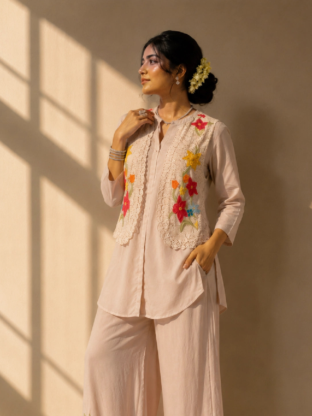 Woman in a beige kurta set with a short floral embroidered jacket and palazzo pants.