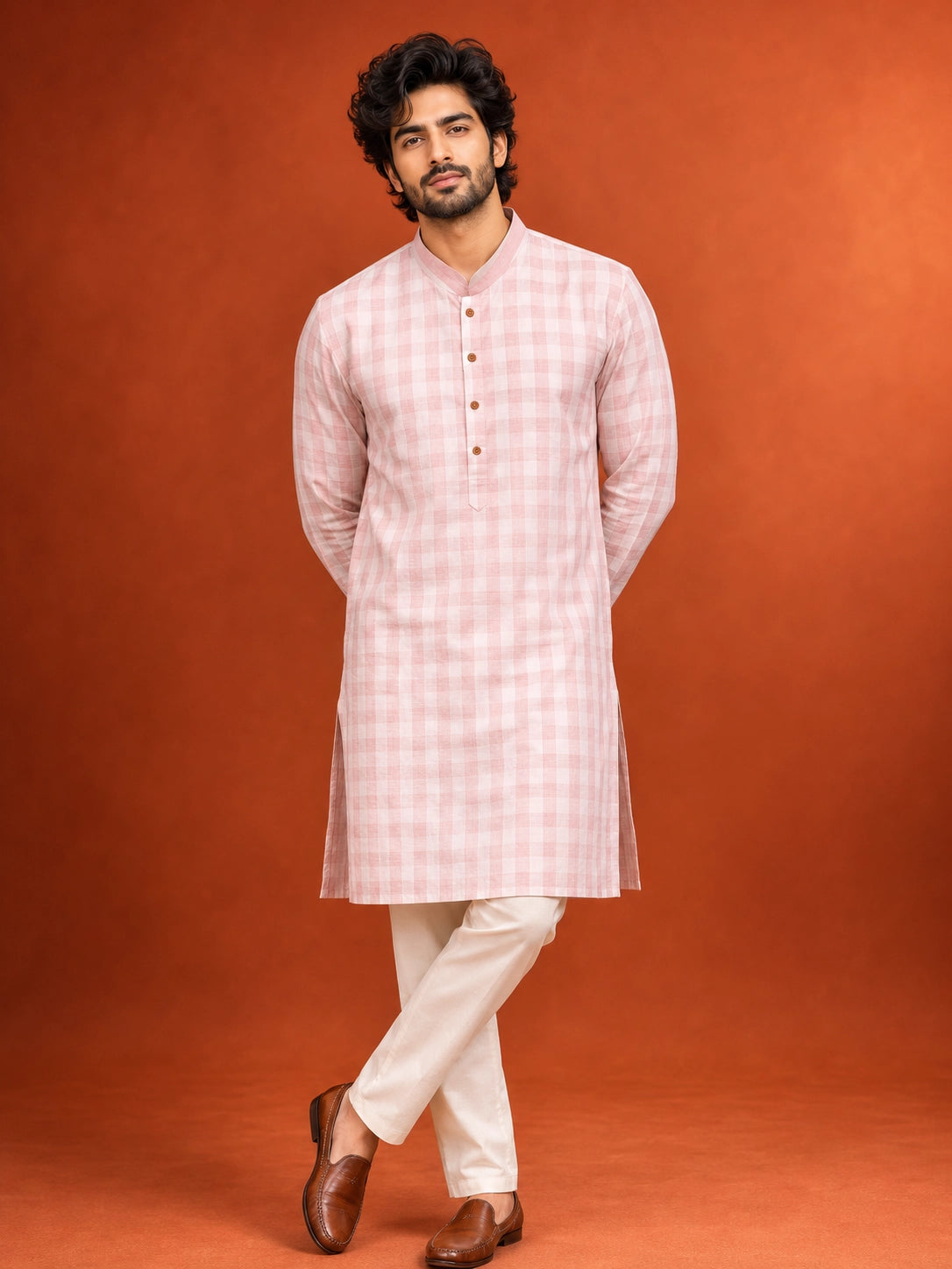 Man wearing a light pink checked kurta with a band collar and white pajama.