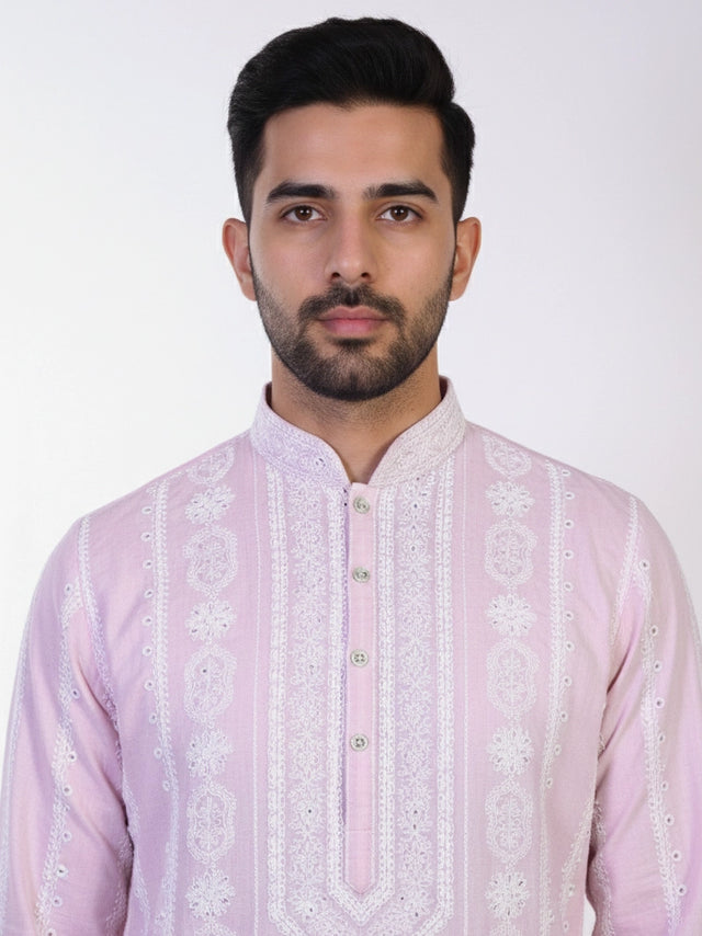 Man wearing a pink chikankari kurta with white churidar pants and brown embellished juttis.