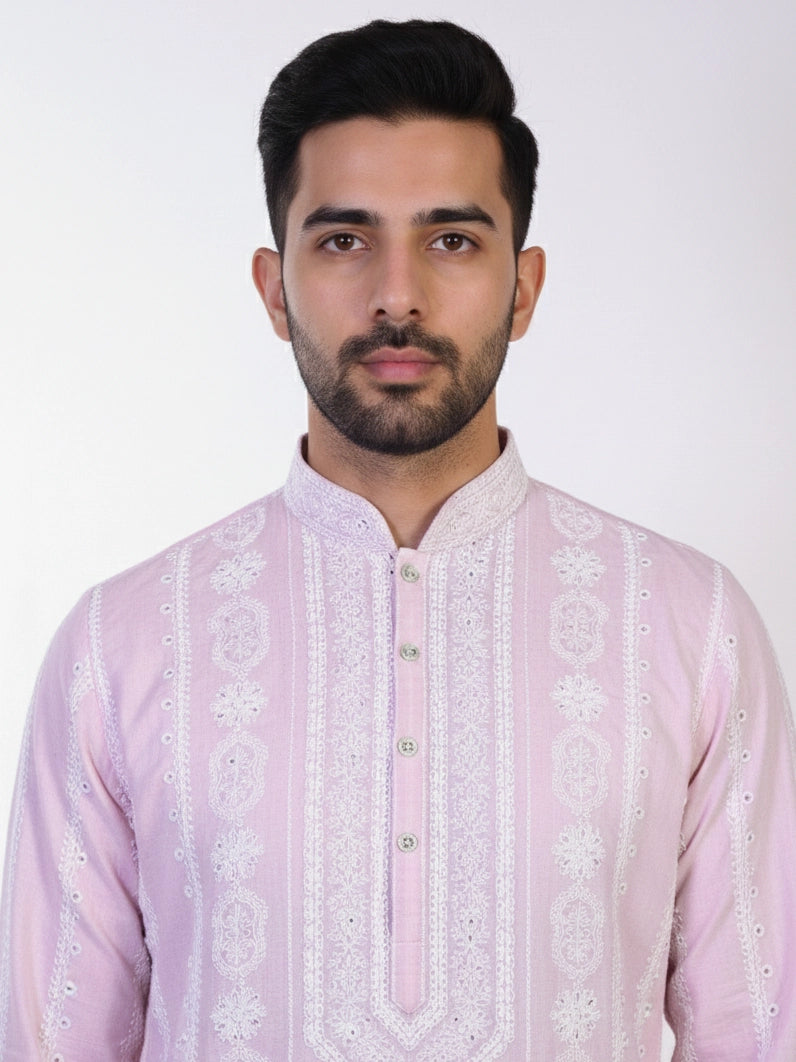 Man wearing a pink chikankari kurta with white churidar pants and brown embellished juttis.