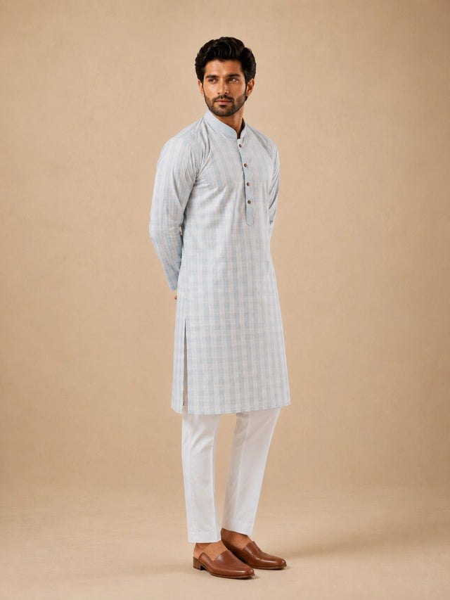 Man wearing a light sky blue and white checkered kurta with white pajamas.