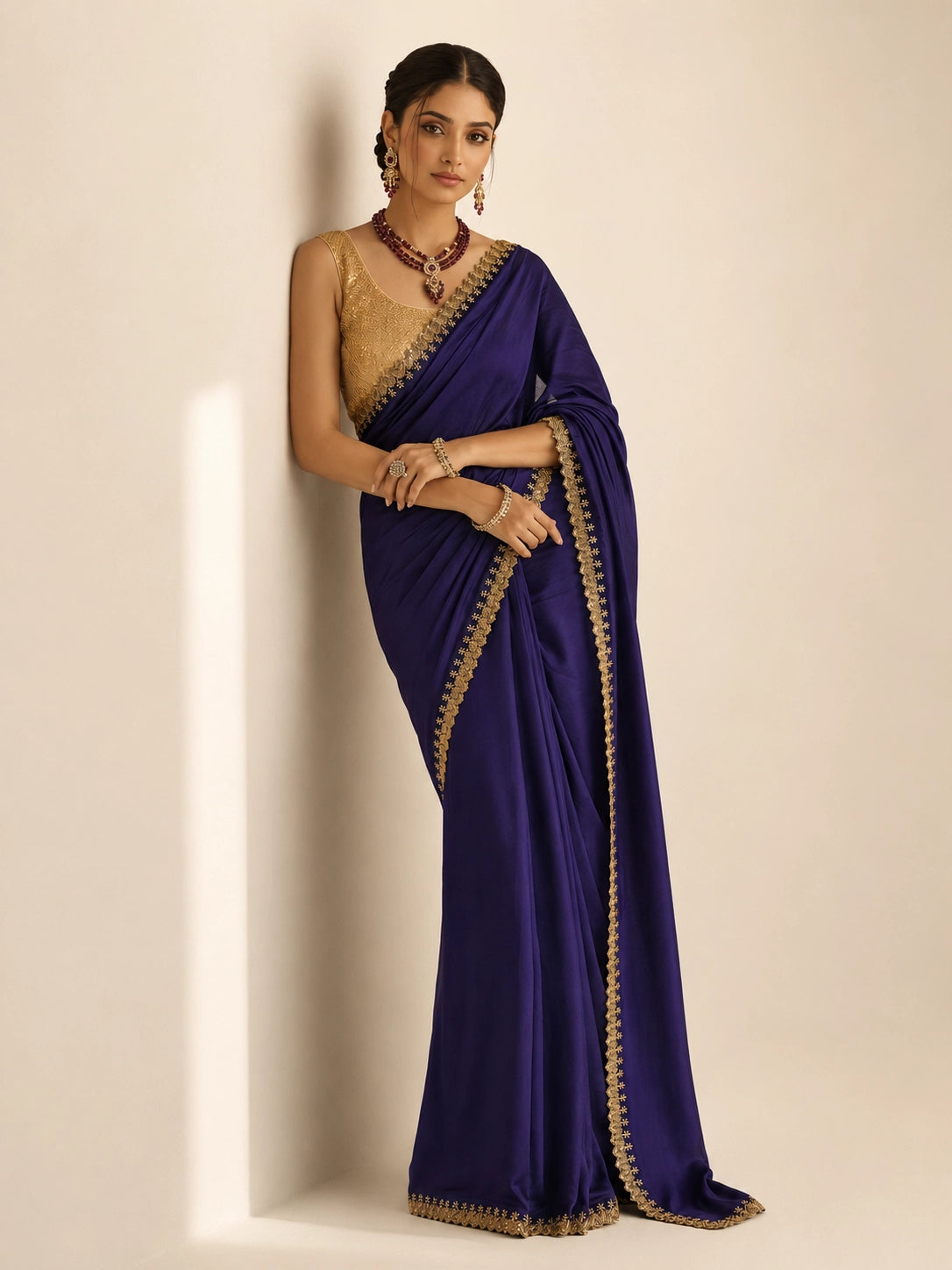 Woman in a purple saree with golden border and matching golden blouse.