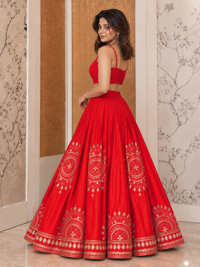 Woman in vibrant red lehenga choli with gold embroidery and matching dupatta.