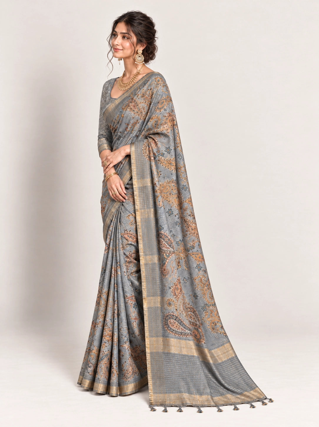 Woman in an elegant lavender grey saree with gold border and intricate paisley patterns.