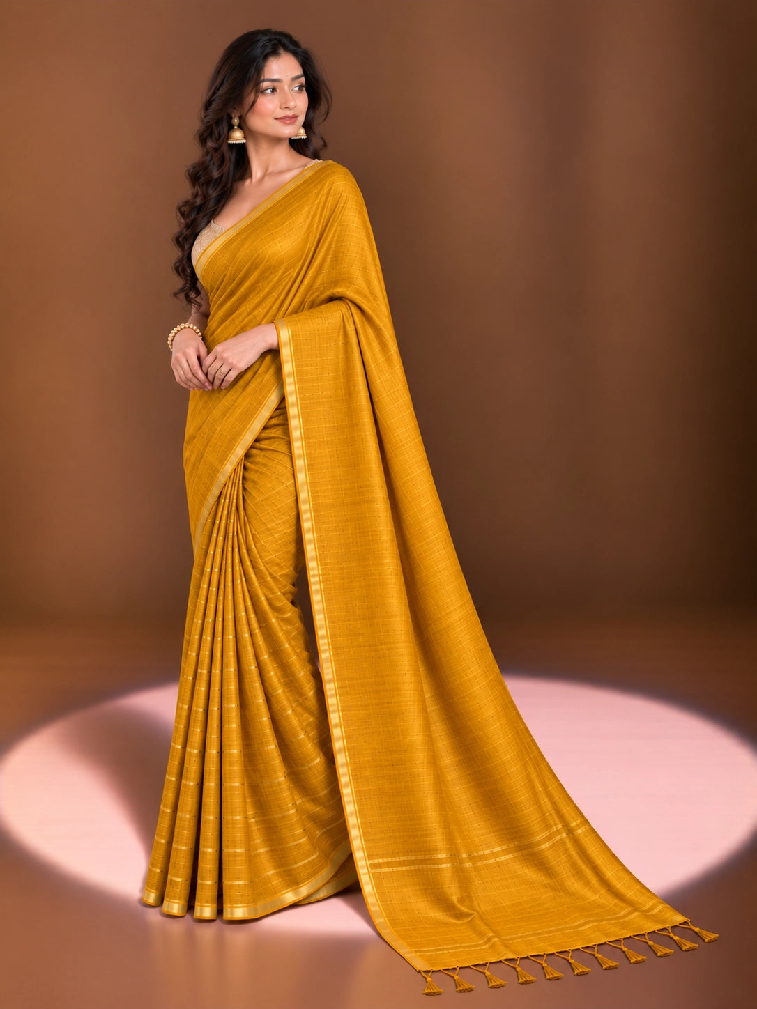 Woman modeling an elegant mustard yellow saree with a subtle woven pattern and golden border.
