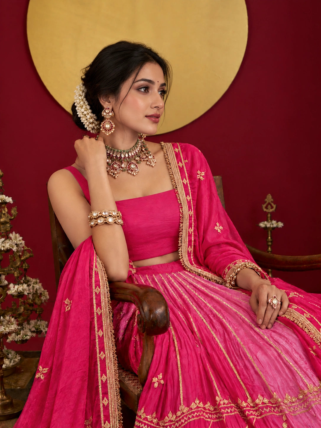 Woman in a vibrant rani pink ombre lehenga choli with gold embroidery.