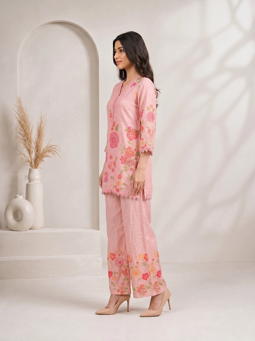 Woman wearing a pink floral print kurta with matching palazzo pants and lace trim.