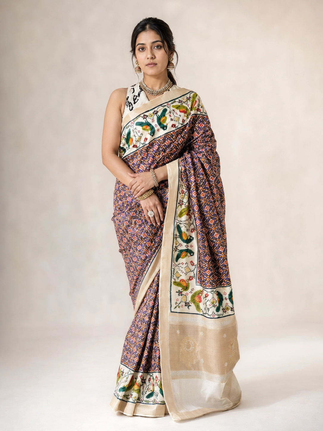 Woman in a purple  saree with intricate bird and floral patterns on pallu.