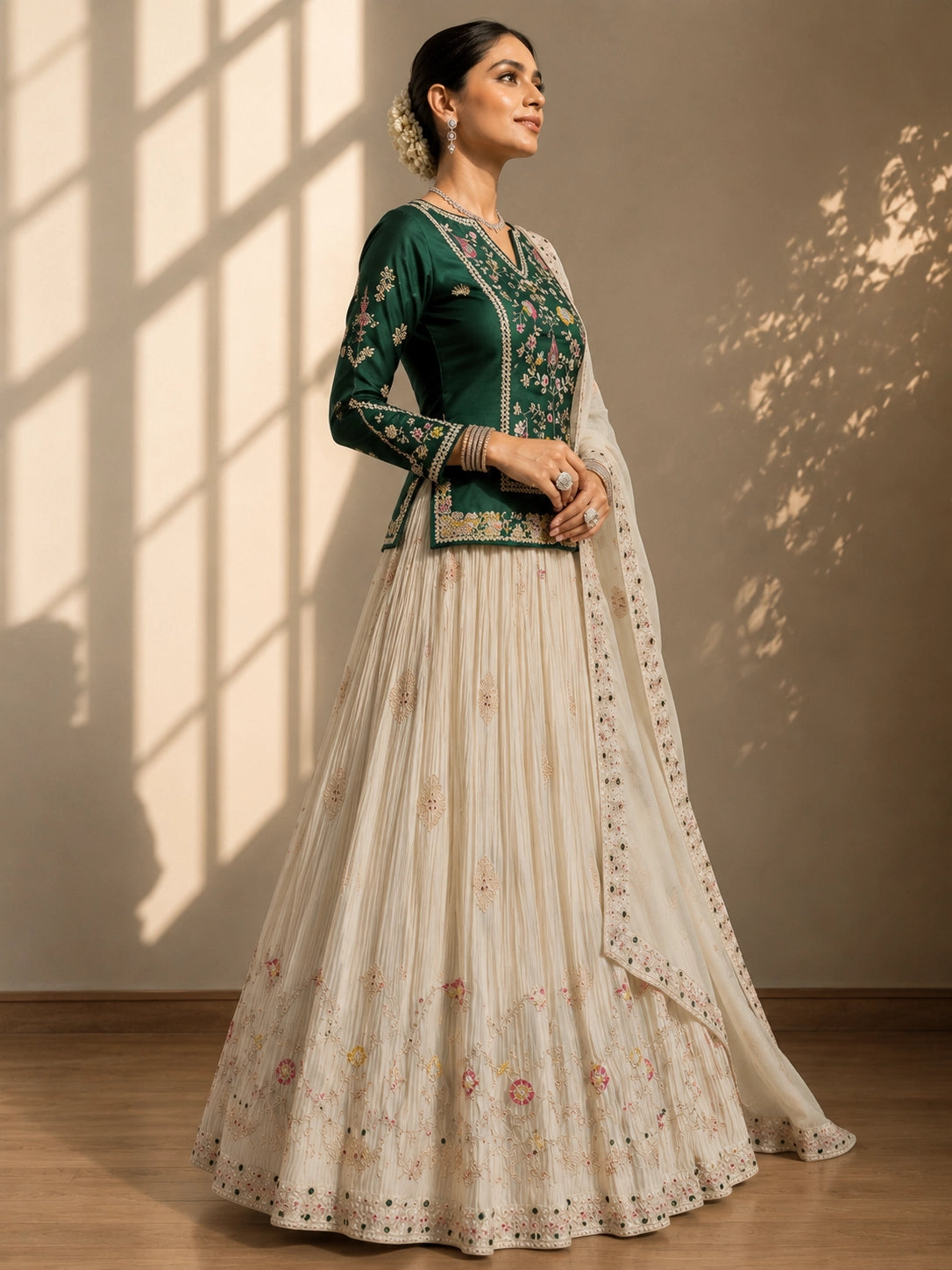 Elegant woman in a dark green embroidered kurta, cream pleated skirt, and matching dupatta.