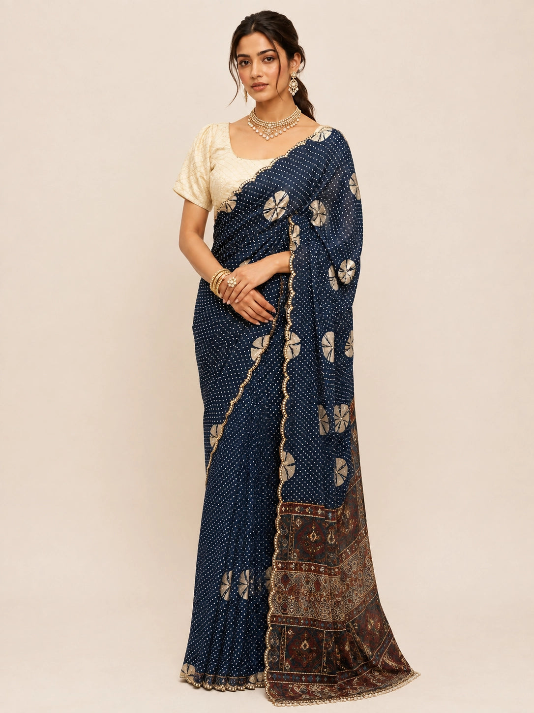 Woman in navy blue bandhani saree with cream blouse and gold jewelry.