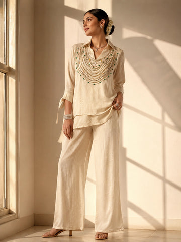 Woman wearing an elegant beige embroidered kurti with wide-leg palazzo pants.