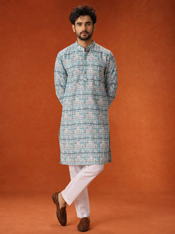 Man wearing an aqua and white printed kurta with white pajamas and brown loafers.