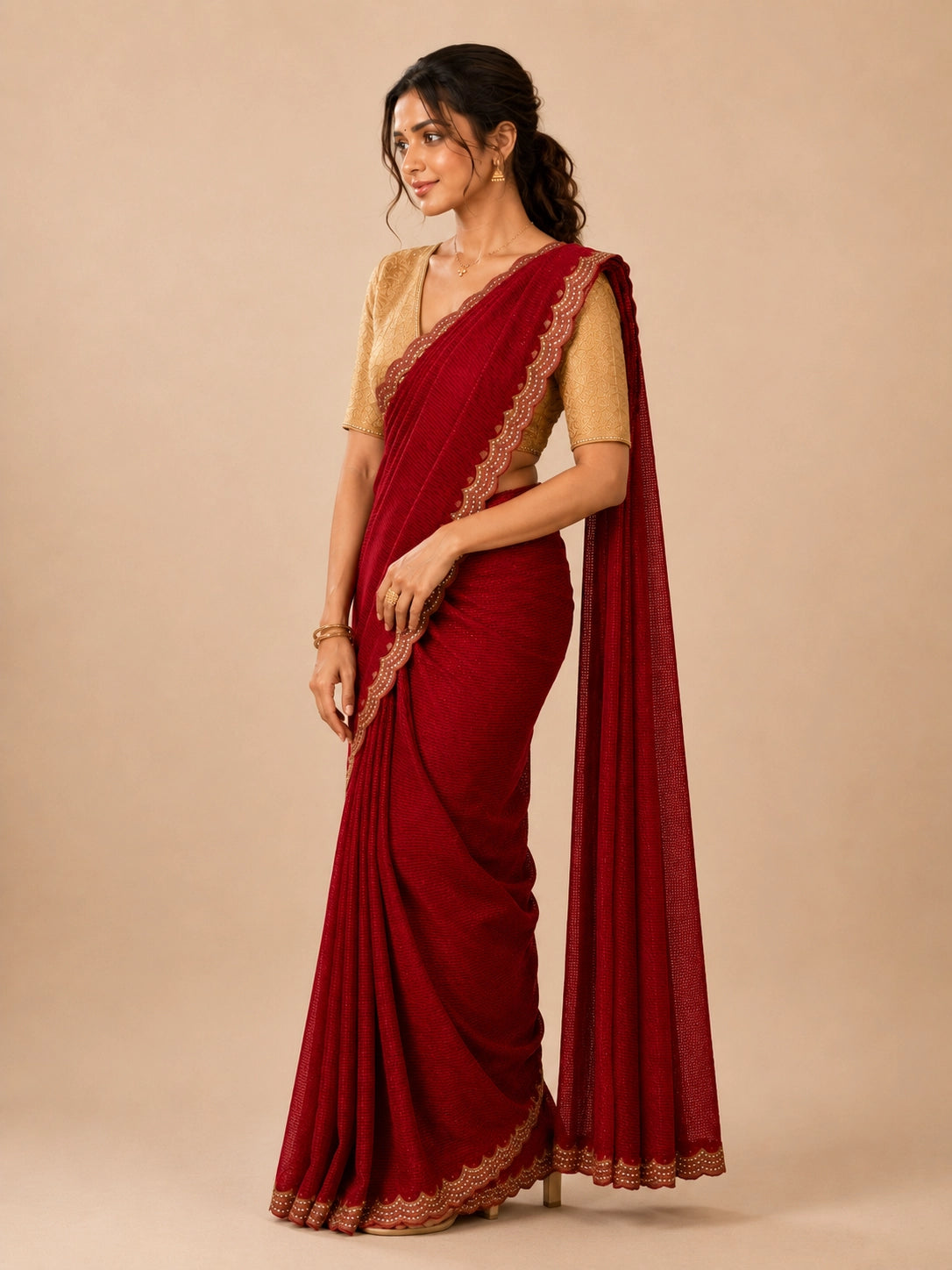 Woman in elegant red pleated saree with embellished border and golden blouse.