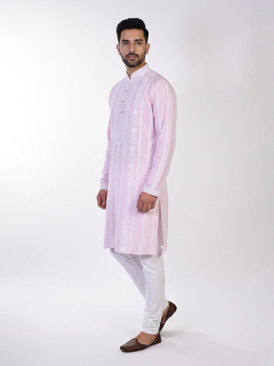 Man wearing a pink chikankari kurta with white churidar pants and brown embellished juttis.