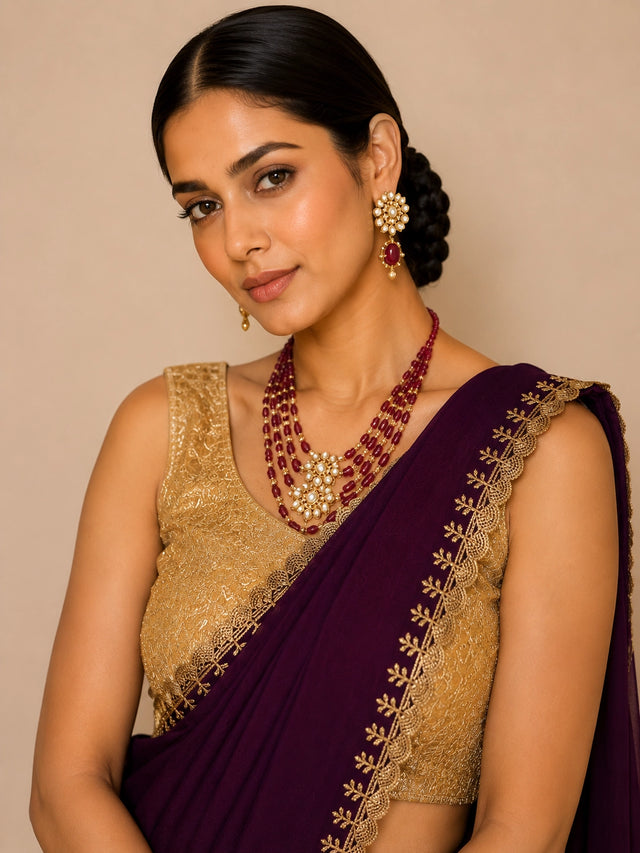 Woman in elegant wine saree with golden embroidered border and matching blouse