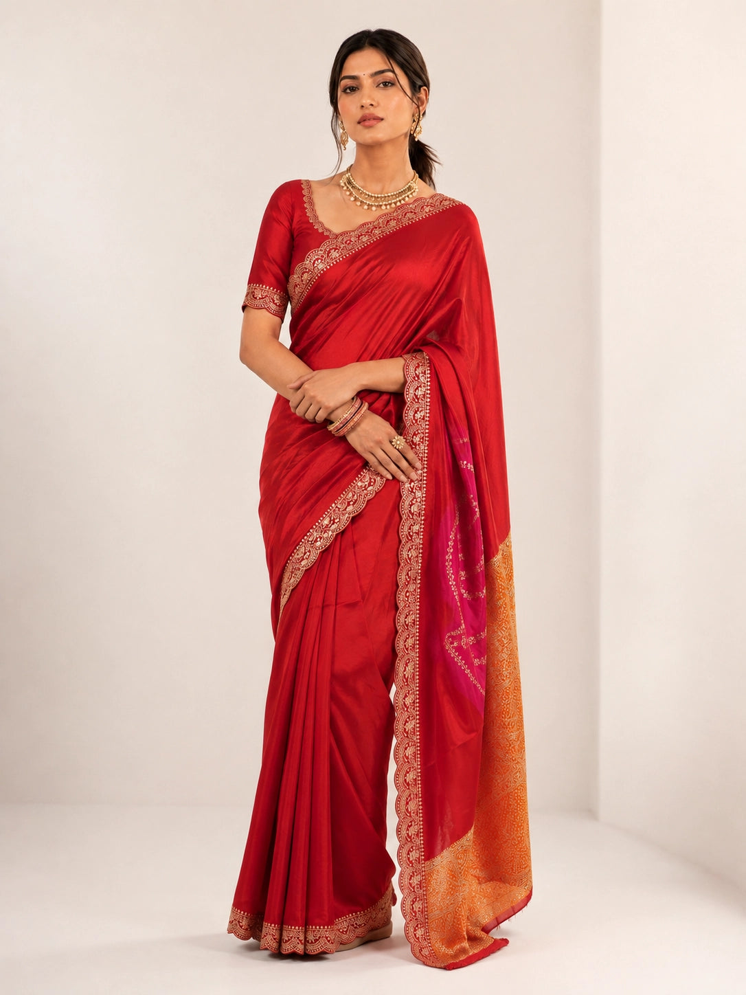 Woman wearing a luxurious red saree with golden embroidered borders and a vibrant pallu.