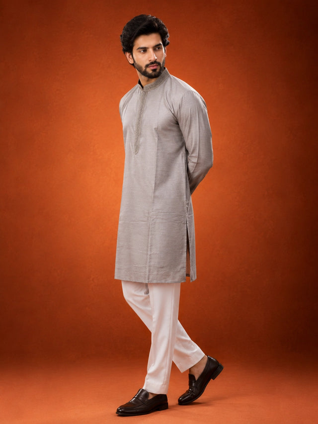 Man in elegant grey kurta with embroidered collar and white pajama set.