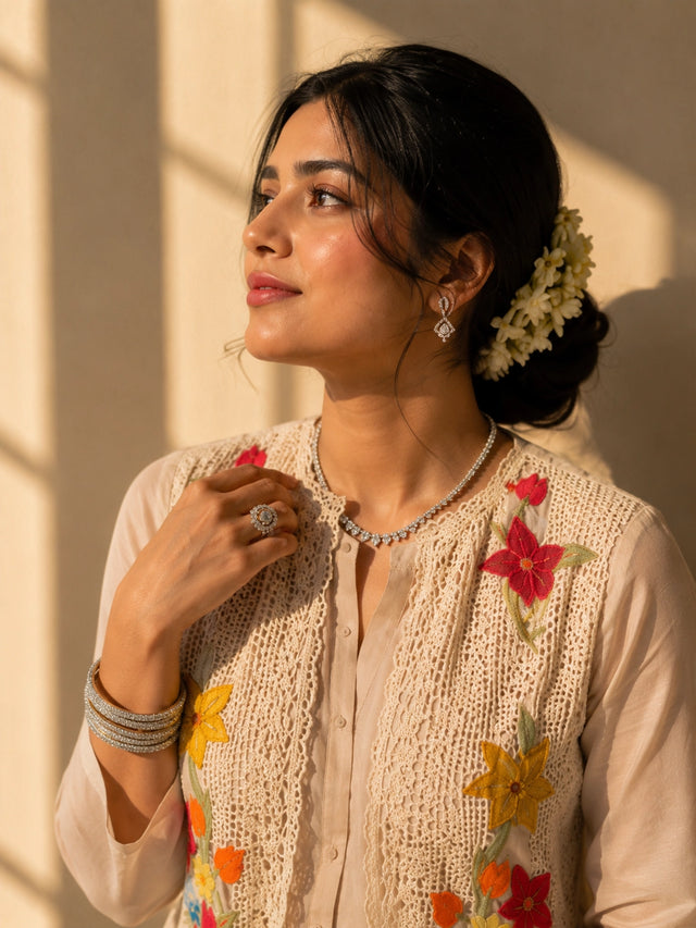 Woman in a beige kurta set with a short floral embroidered jacket and palazzo pants.