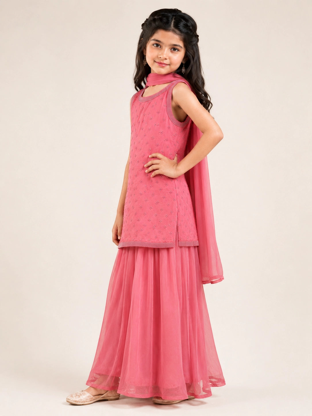 Young girl in a pink sleeveless kurta with beaded embroidery and flowy pink sharara pants.