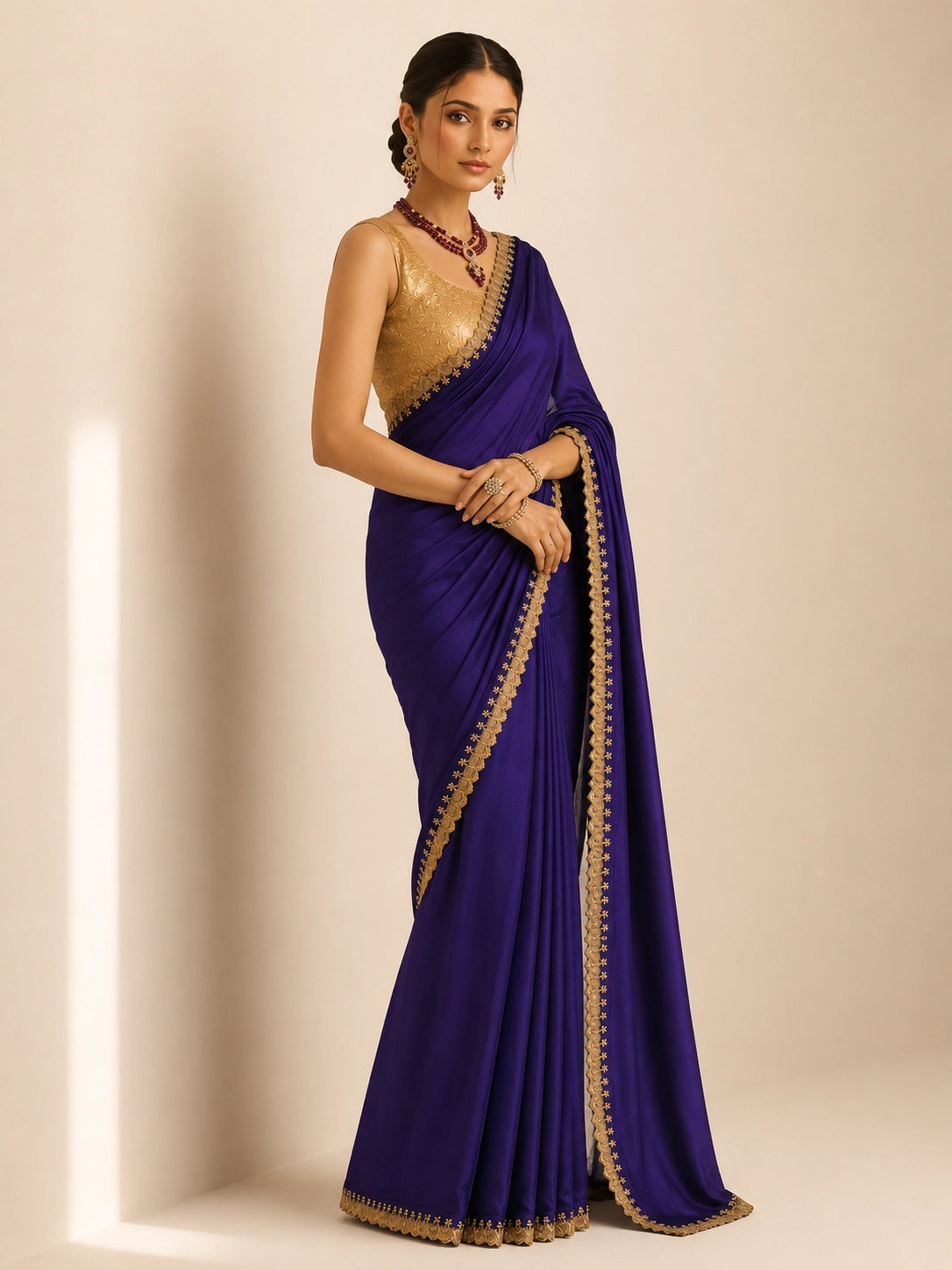 Woman in a purple saree with golden border and matching golden blouse.