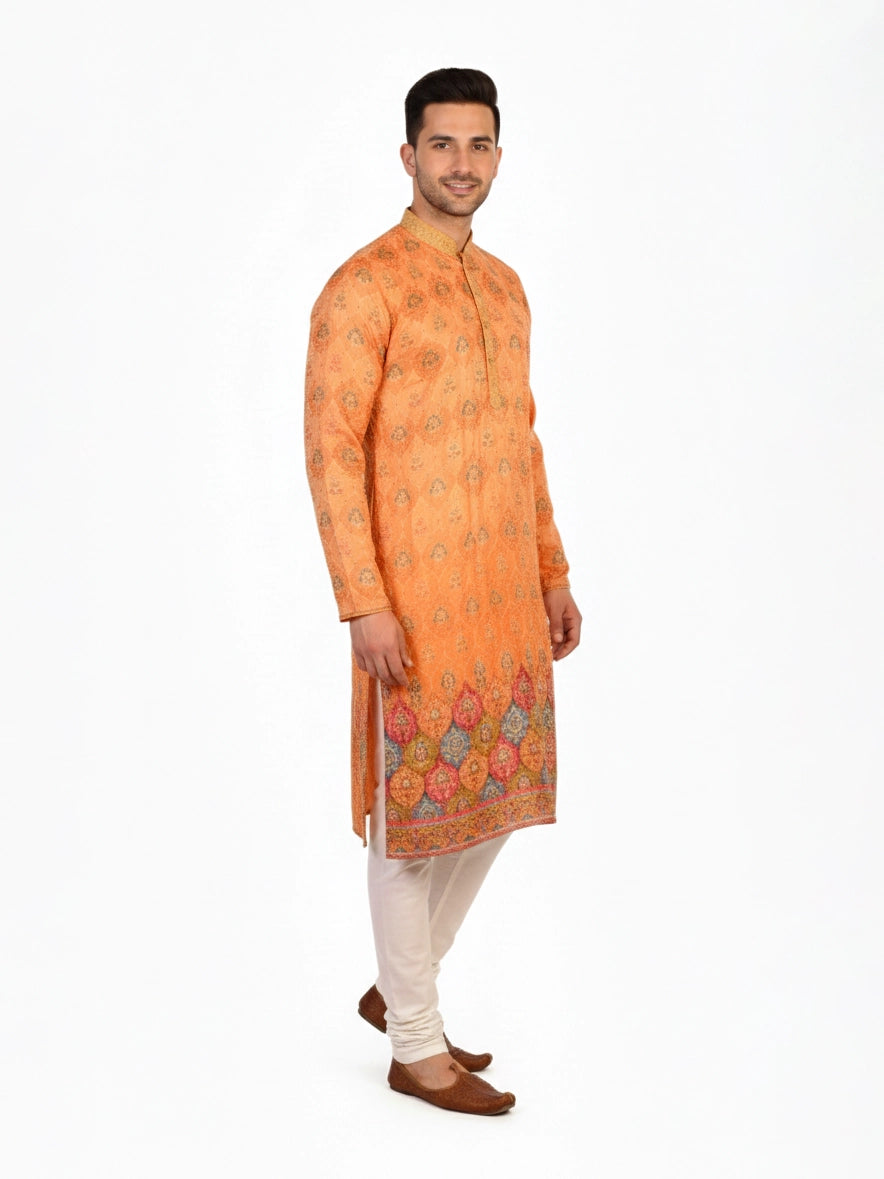 Man wearing an orange embroidered Kurta Pajama with cream pants and brown shoes, showcasing intricate patterns.