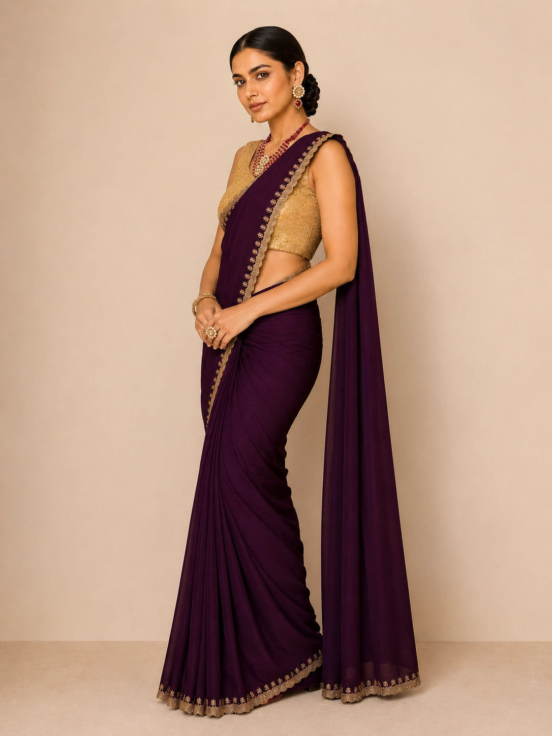 Woman in elegant wine saree with golden embroidered border and matching blouse
