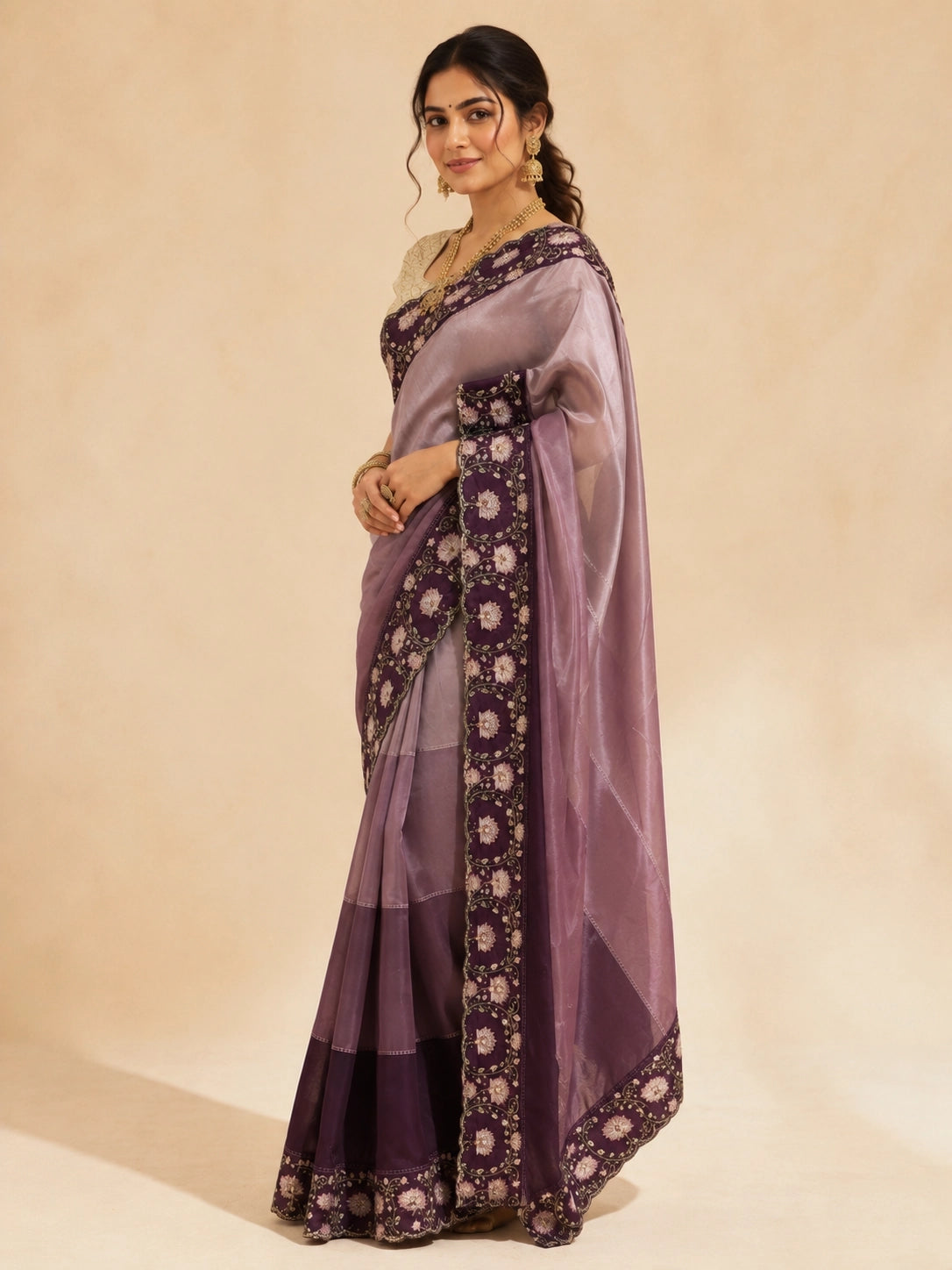 Woman in an elegant wine  saree with intricate floral embroidery and a golden blouse.