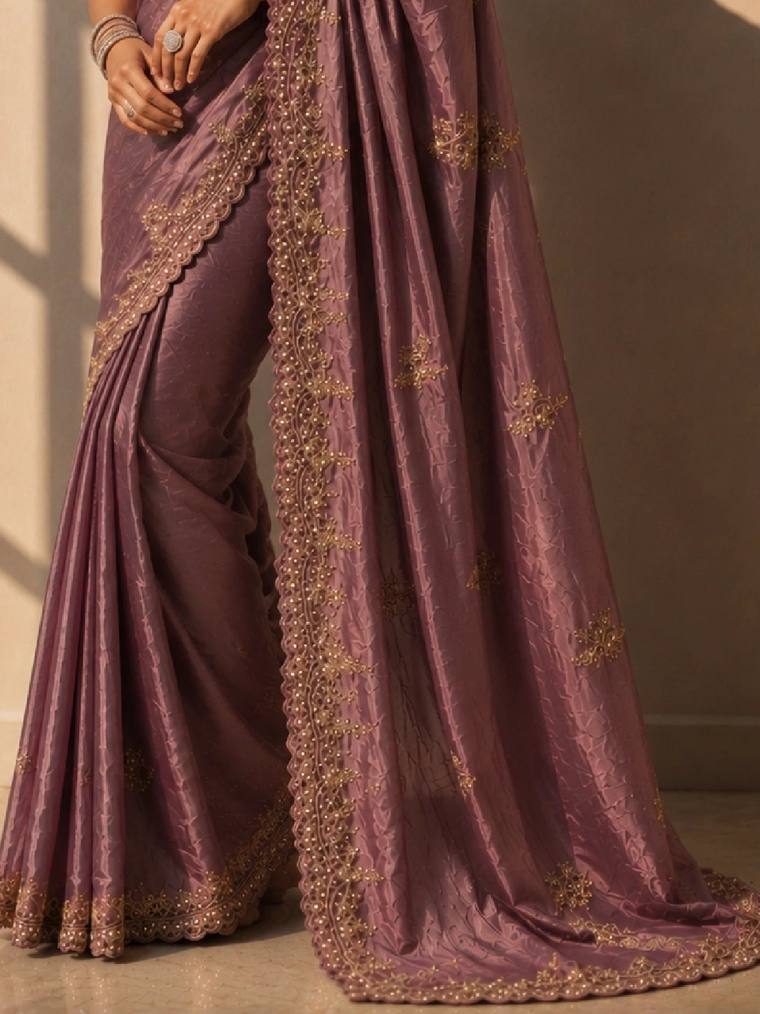 Woman in an elegant onion silk saree with intricate gold embroidery.