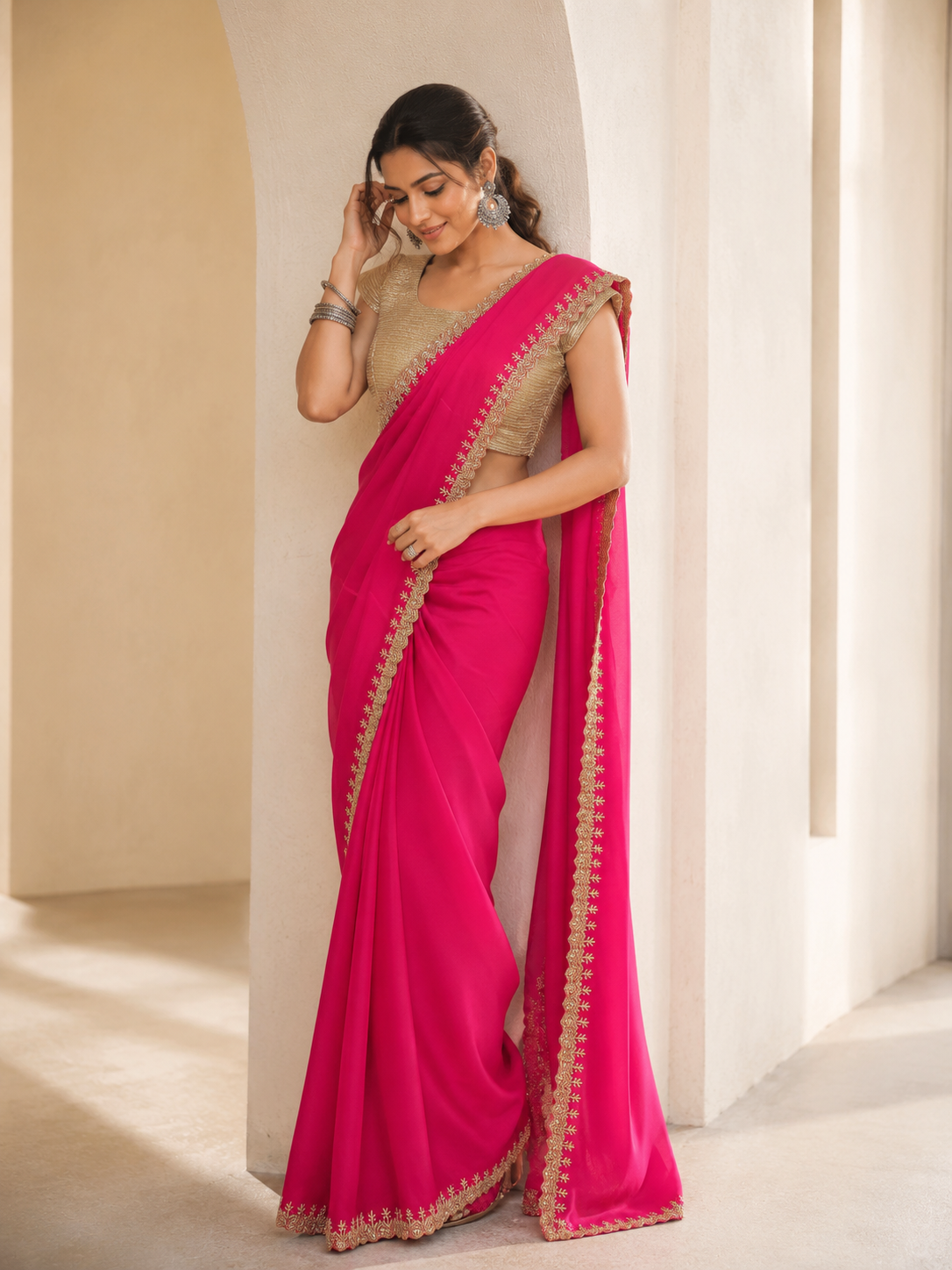 Woman wearing a vibrant rani pink saree with golden embroidered borders and a gold blouse.
