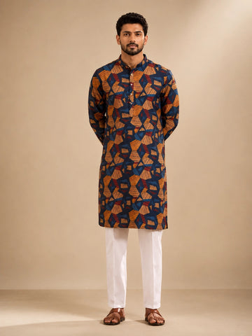 Men's navy kurta with geometric print, paired with white pajama bottoms and brown sandals.