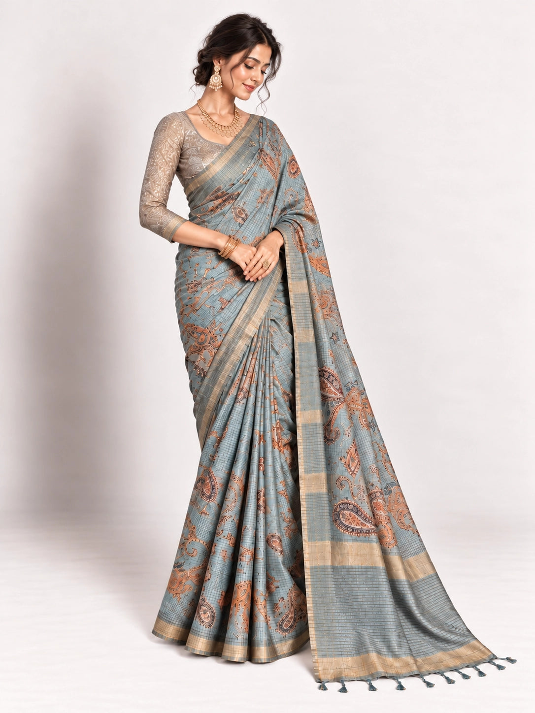 Woman in an elegant lavender grey saree with gold border and intricate paisley patterns.