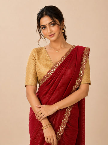Woman in elegant red pleated saree with embellished border and golden blouse.