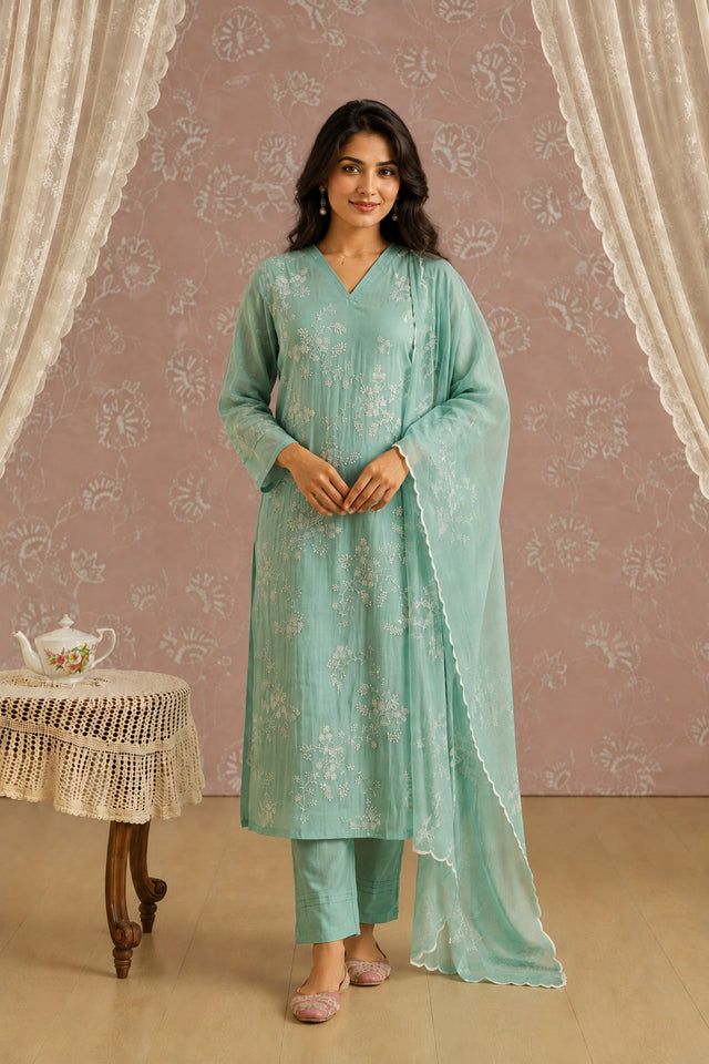 Woman wearing an elegant light green kurti with intricate white floral embroidery.