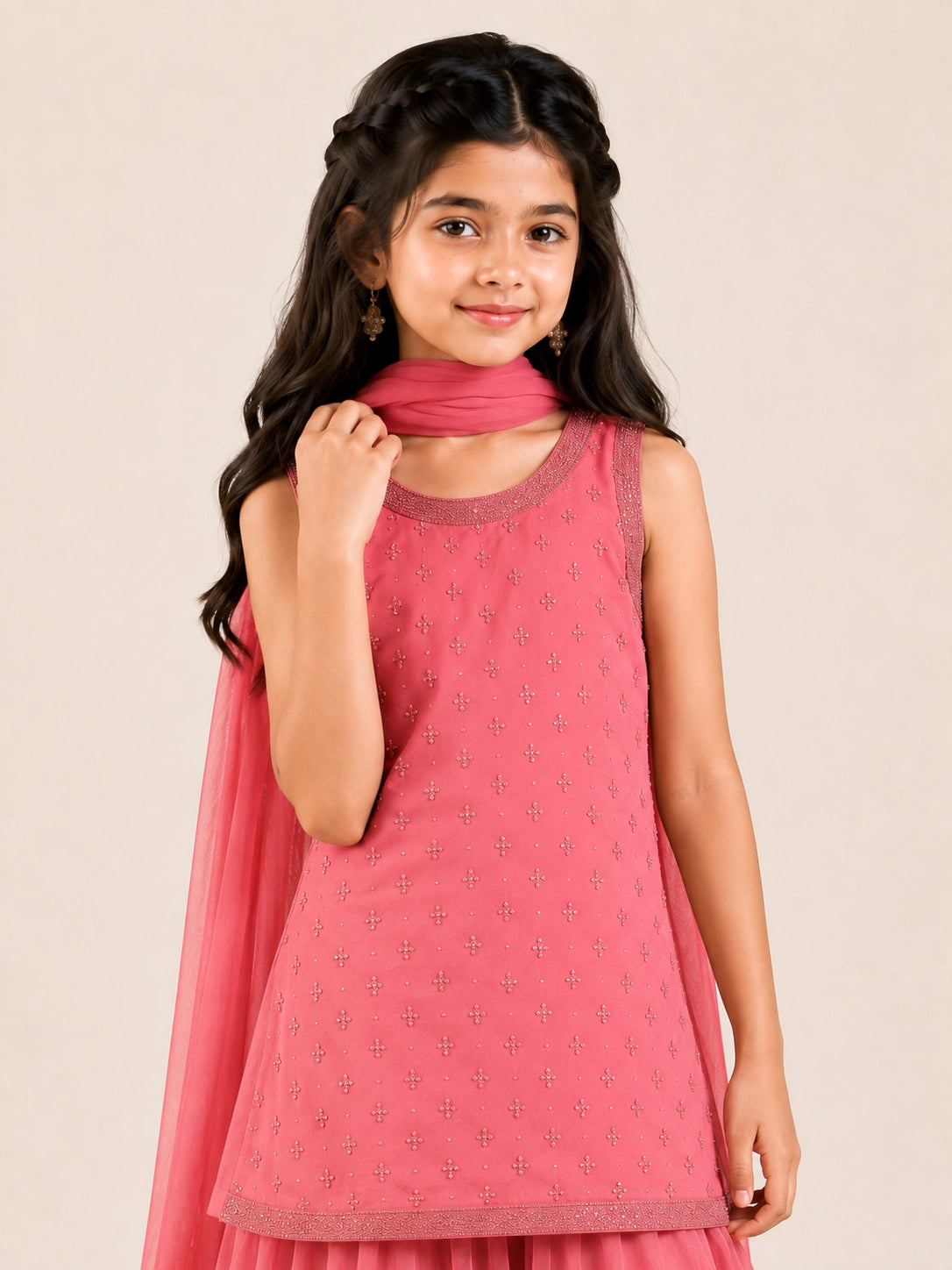 Young girl in a pink sleeveless kurta with beaded embroidery and flowy pink sharara pants.