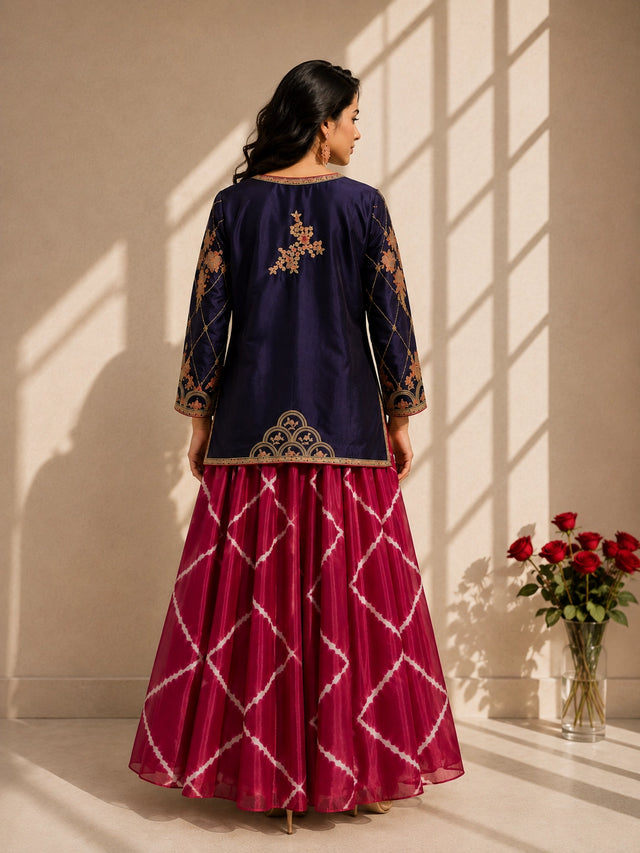 Elegant woman wearing a blue embroidered jacket with a pink tie-dye kurti set.