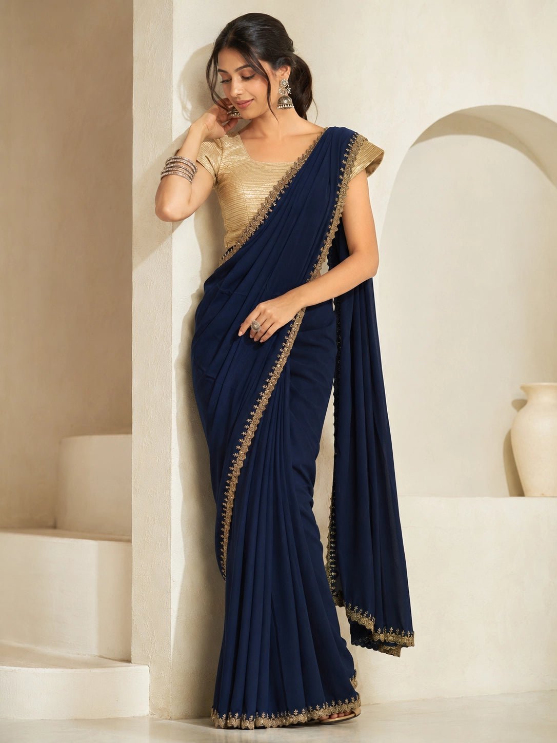 Woman wearing a navy blue saree with gold embroidered borders and a gold blouse.
