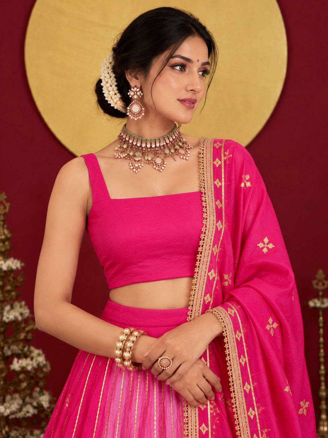 Woman in a vibrant rani pink ombre lehenga choli with gold embroidery.