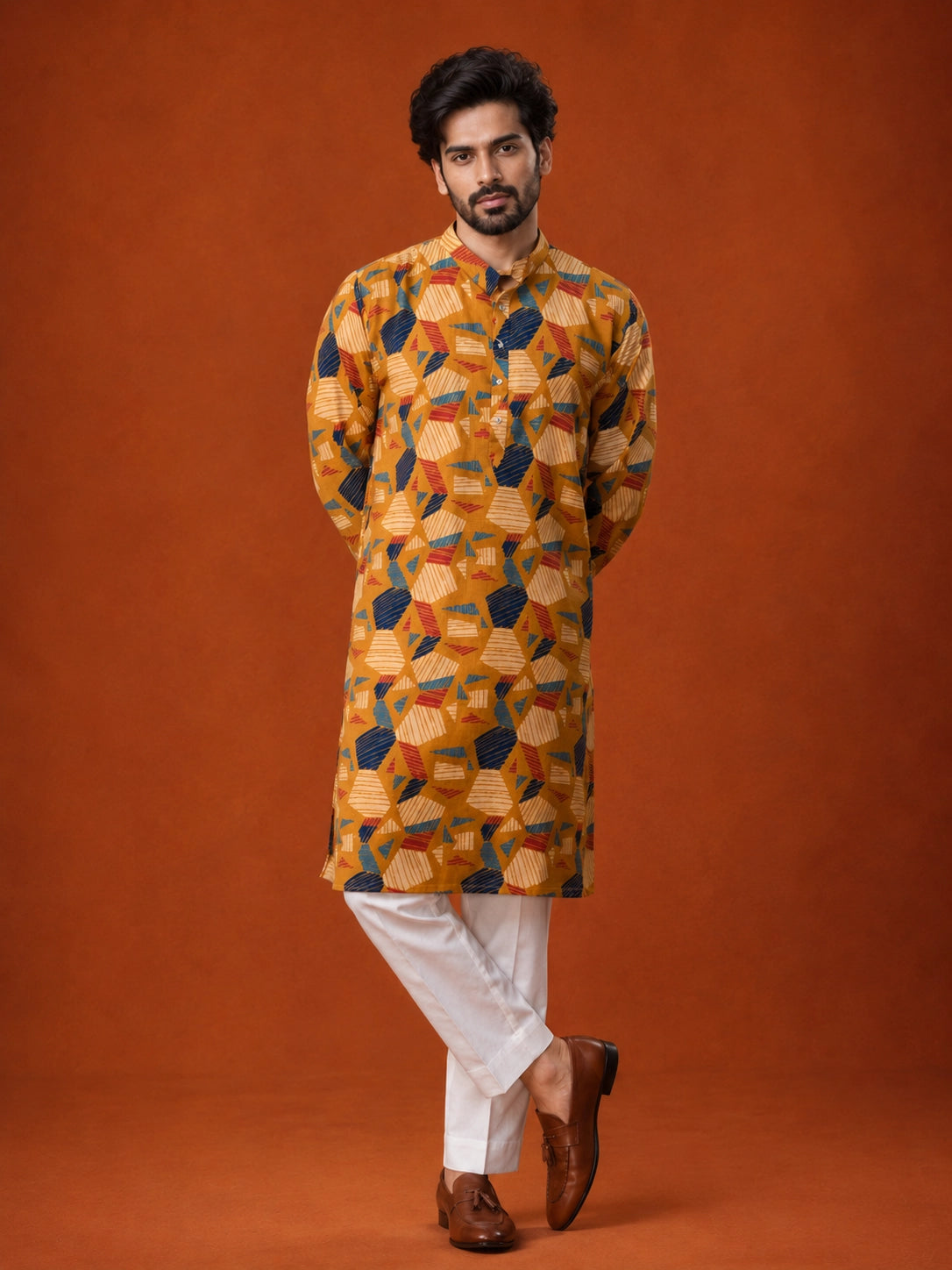 Man wearing a mustard kurta with blue, red, and white geometric print and white pajama.