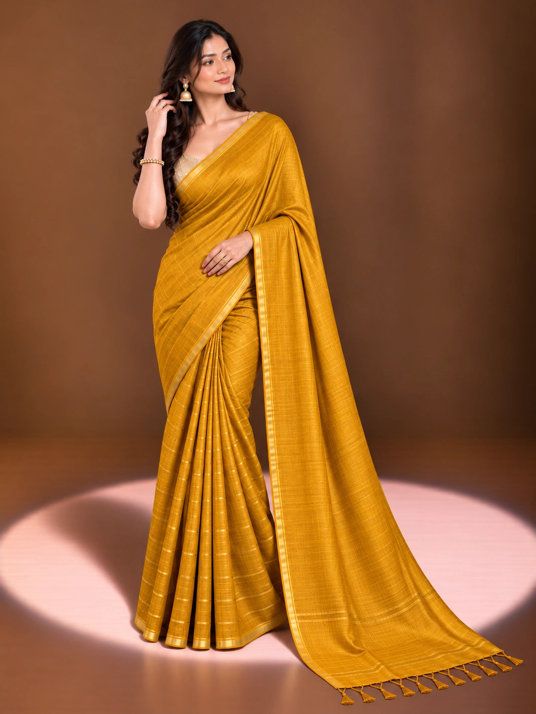Woman modeling an elegant mustard yellow saree with a subtle woven pattern and golden border.
