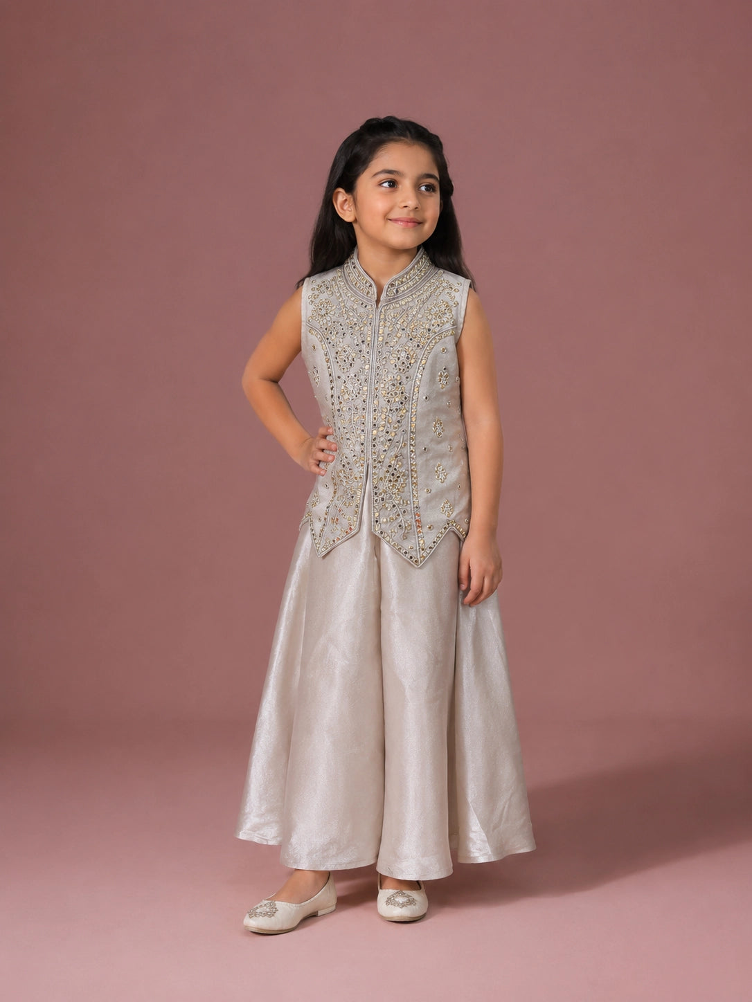 A young girl in a cream embroidered sleeveless top and matching wide-leg palazzo pants.