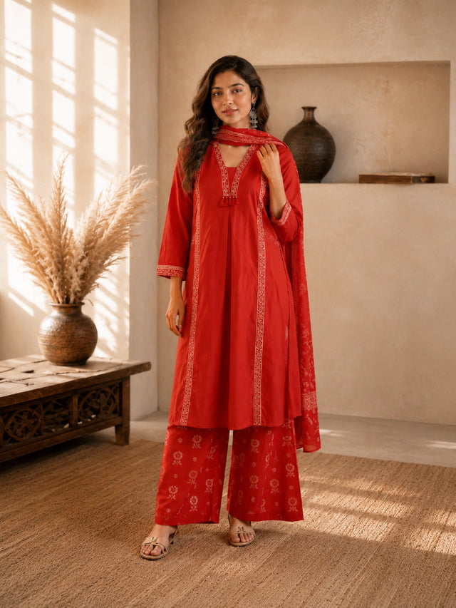 Woman wearing a rust-colored printed cotton kurti and pants set with intricate border details.