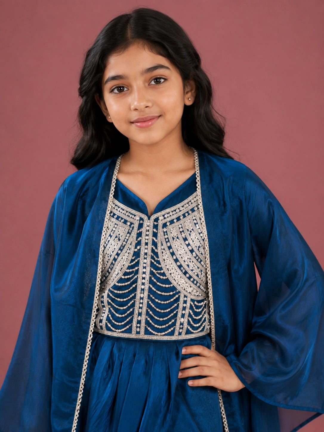 Young girl wearing a vibrant blue dhoti set with an embellished top and sheer jacket.